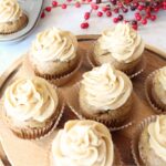 Finished pumpkin cupcakes after decorating with spiced buttercream on a cake stand, red berries in the background