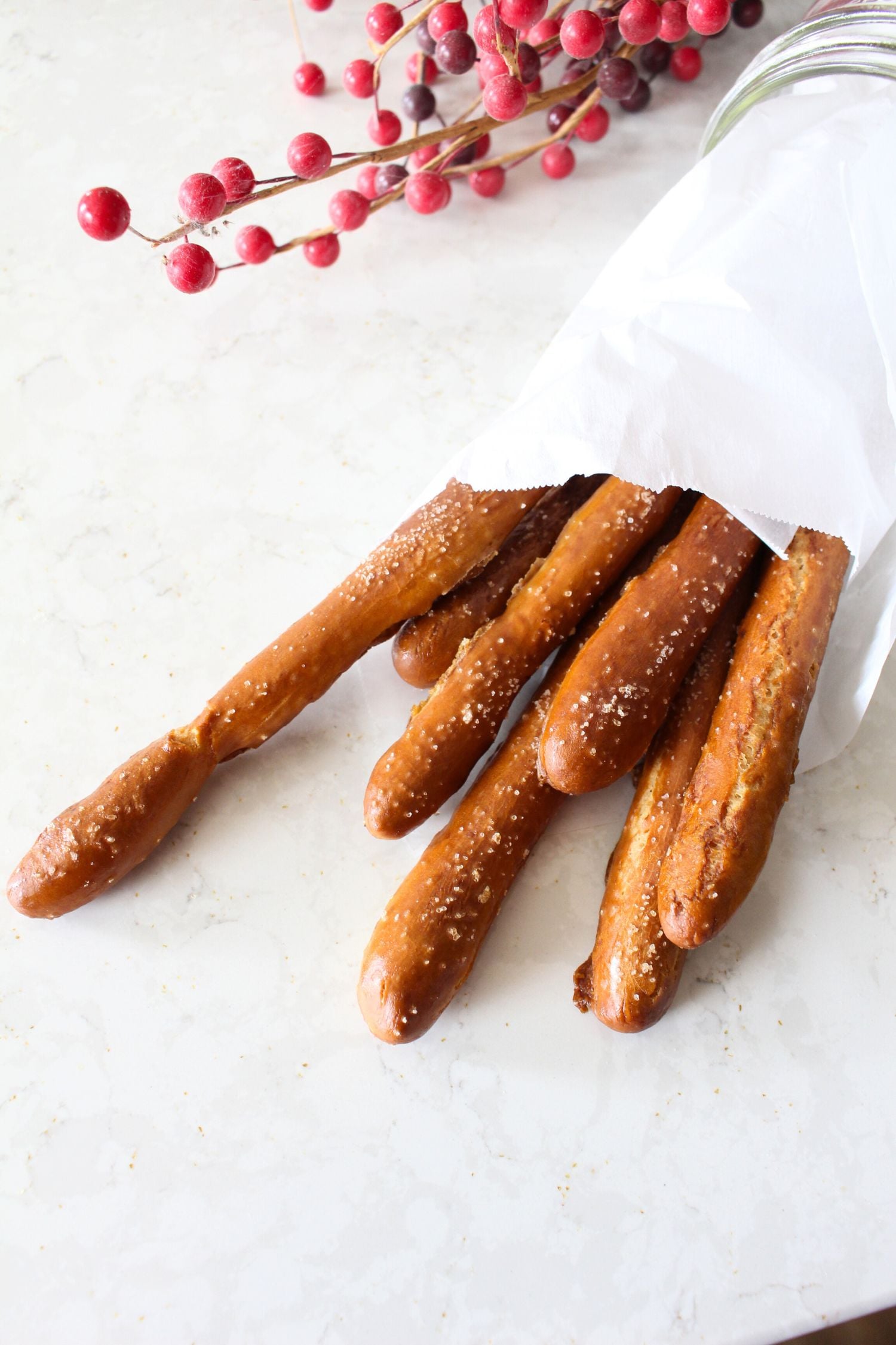 homemade hard pretzel rods in a parchment paper wrap on a white countertop.