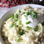 Finished bowl of homemade colcannon potatoes topped with sour cream and green onions