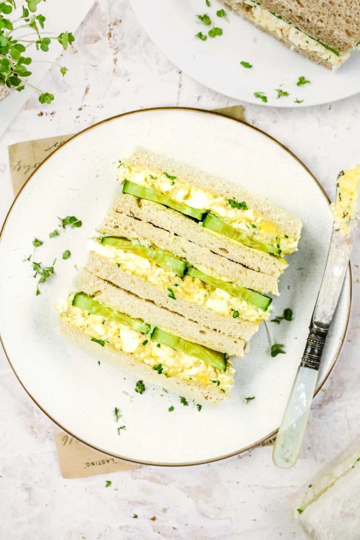 a plate of finished egg and cucumber sandwiches showing the cross section of the filling