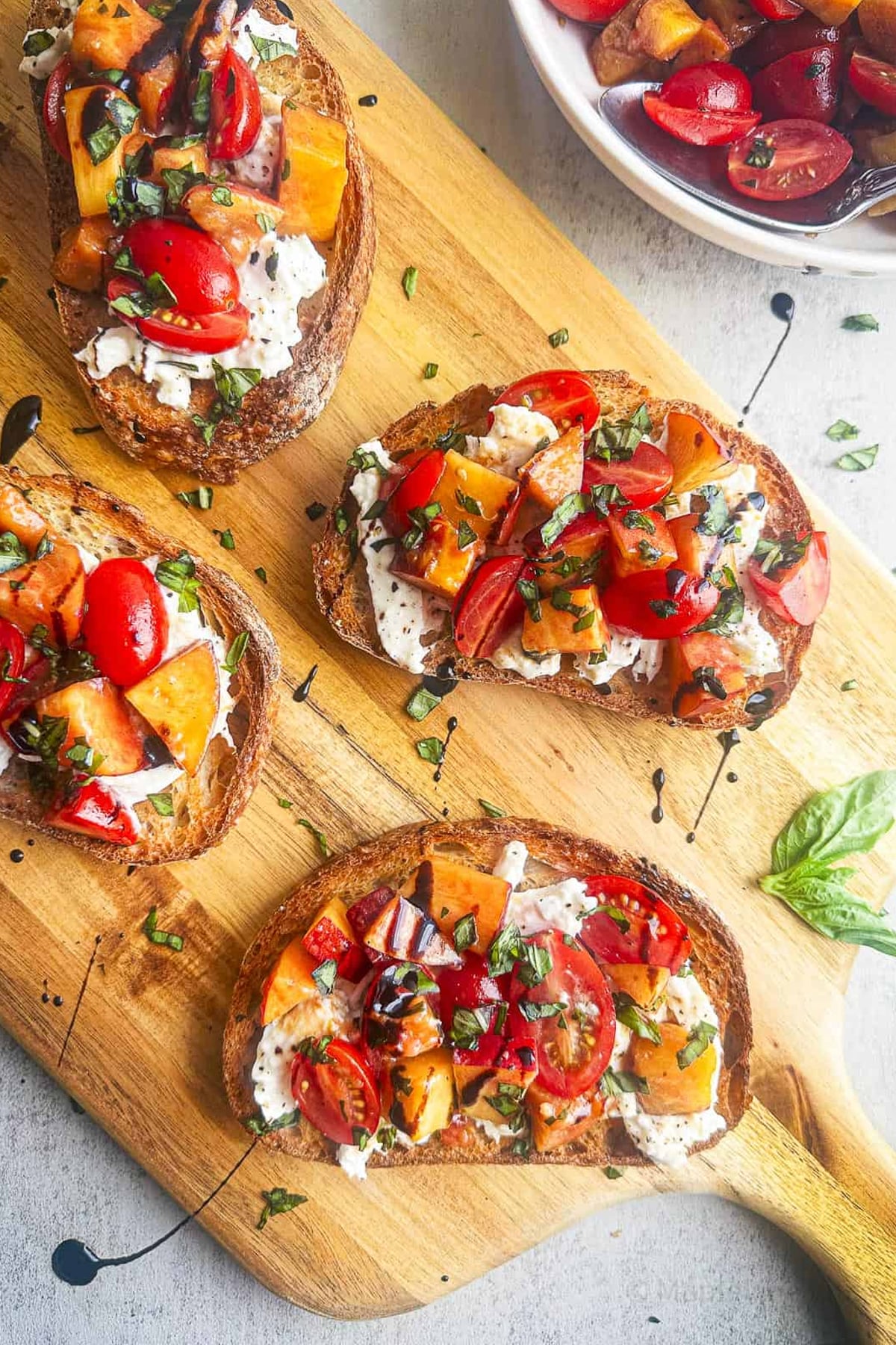 top down view of Burrata Bruschetta with Peaches and Tomatoes on a wooden cutting board