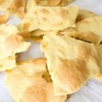 Broken pieces of homemade unleavened bread on parchment paper, ready to use for communion bread or as a snack.