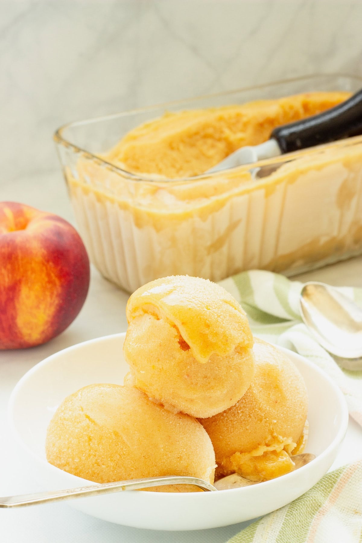 a 3 scoop bowl of No-Churn Peach Sorbet