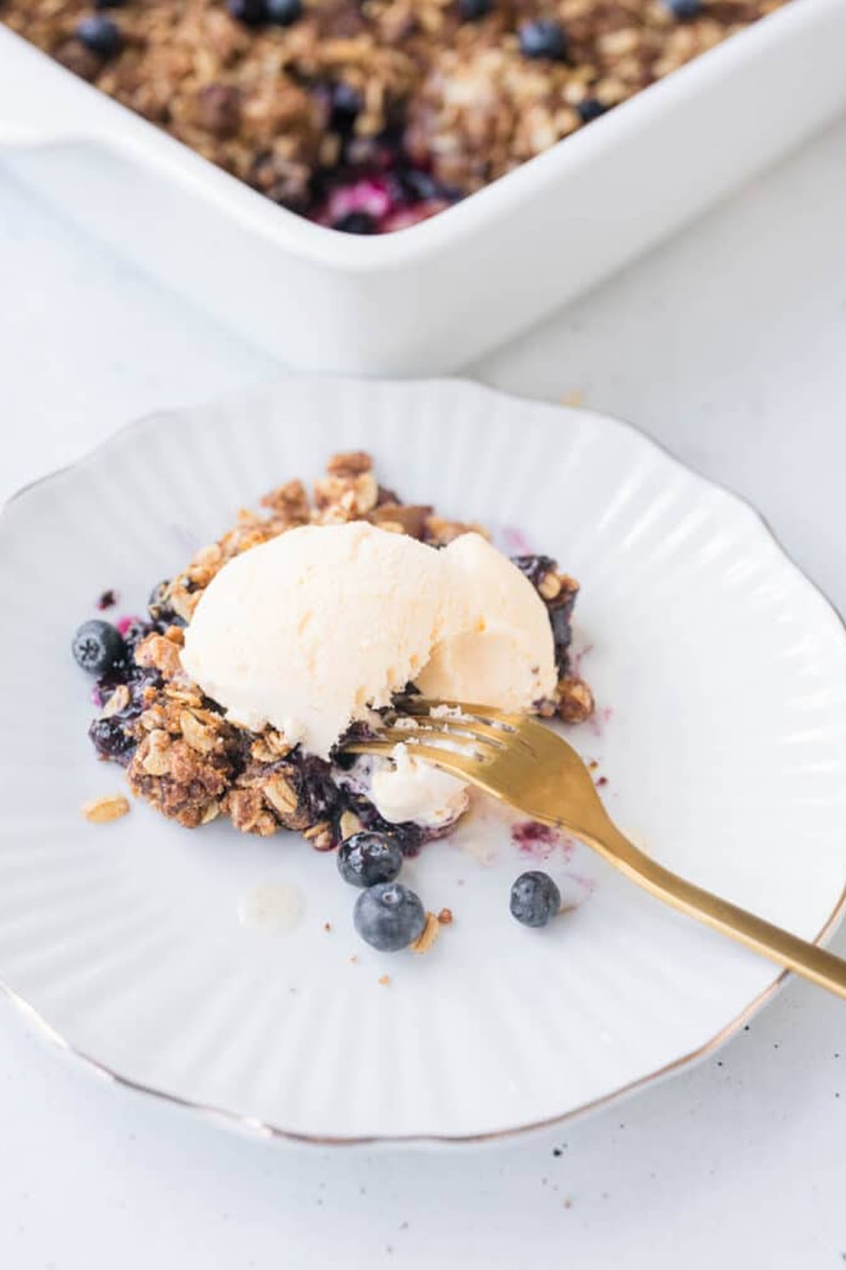 Peach Blueberry Cobbler slice on a white plate with a gold fork