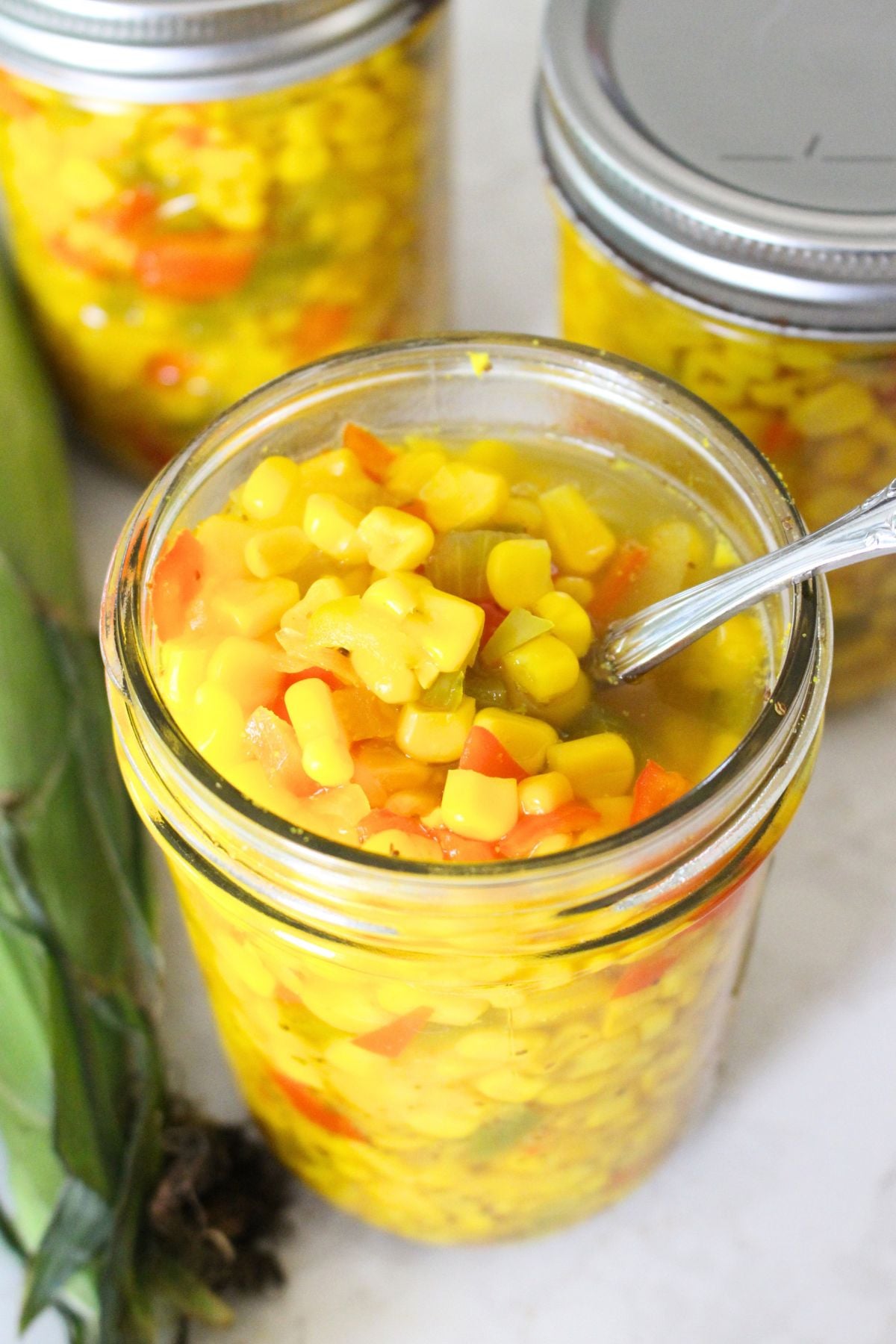 small-batch sweet corn relish in canning jars, one is opened to see the relish