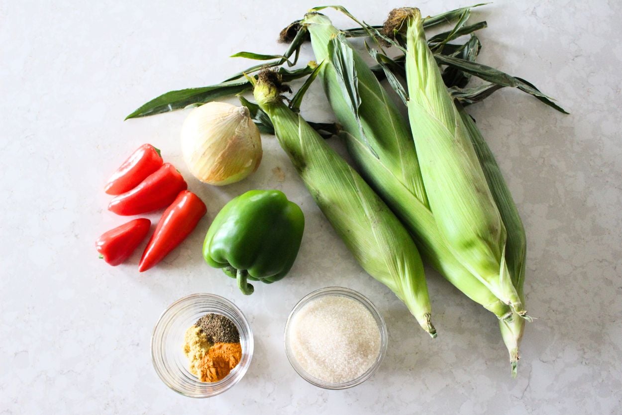 ingredients for sweet corn relish, including fresh corn, peppers, onions, sugar, and spices. 