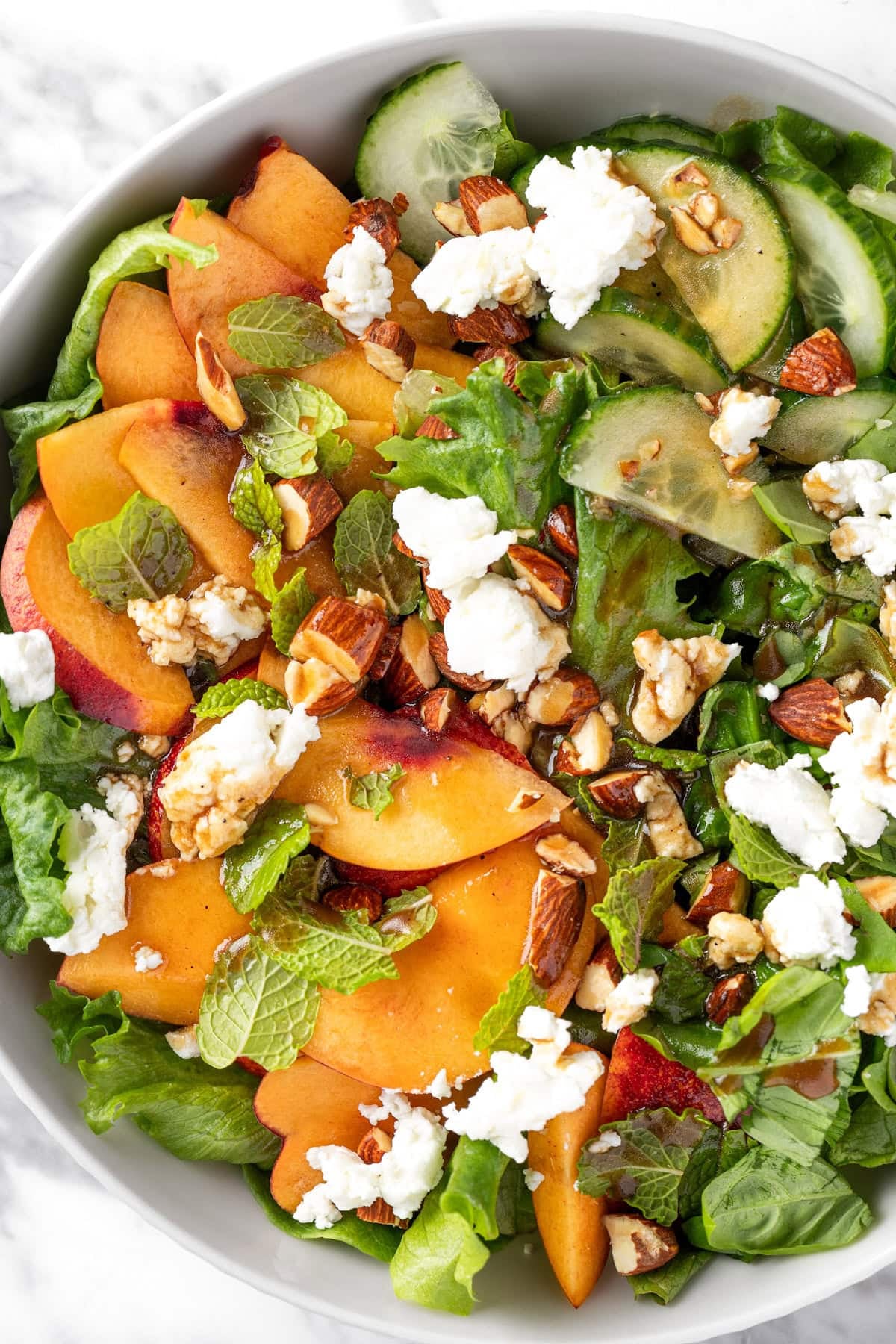 top down view of Sweetgreen Peach And Goat Cheese Salad in a white bowl