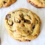 a stack of freshly baked homemade chocolate chip cookies on a parchment lined baking sheet