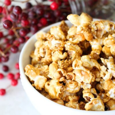 close-up image of a bowl of finished homemade caramel popcorn in a white bowl
