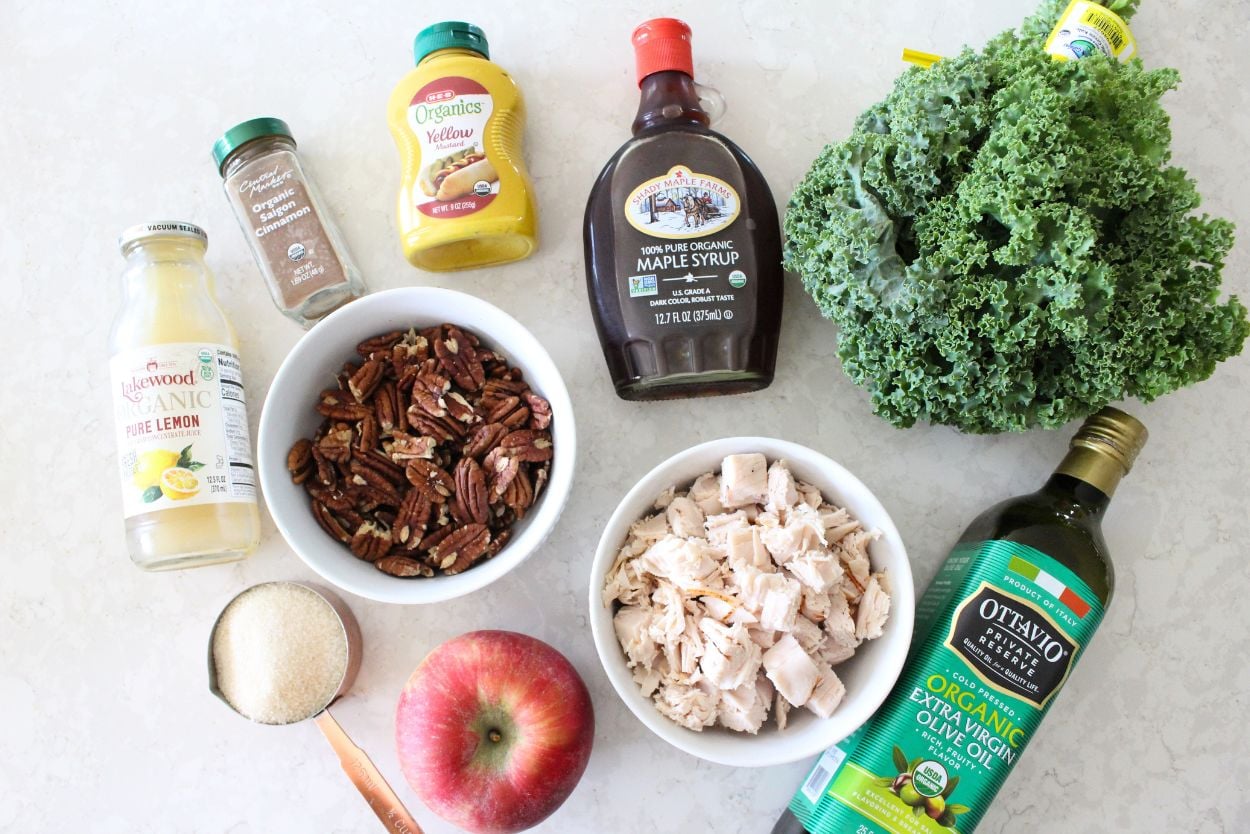 Ingredients for the turkey apple pecan kale salad, including kale, turkey, apples, pecans, maple syrup, sugar, olive oil, mustard, cinnamon, and lemon juice. 