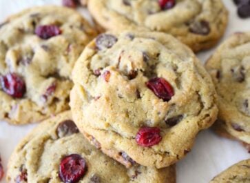 Cranberry pecan chocolate chip cookies with nuts and chocolate chips on baking sheet